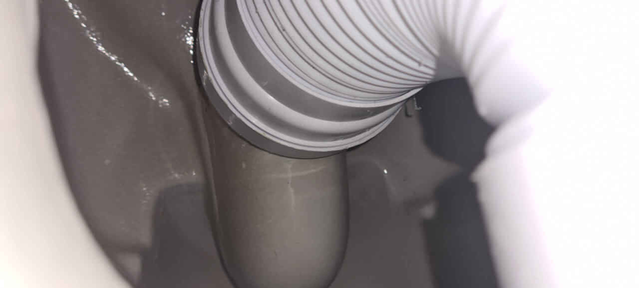 Toilet pan being installed using flexible pan connector into soil pipe