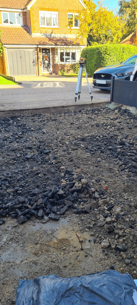 Using a laser level to grade the site to the required levels using the MoT Type 1 and crush