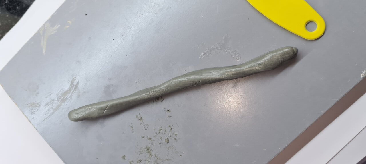 Two part epoxy putty rolled out into thin sausage shape ready to go round pipe joint