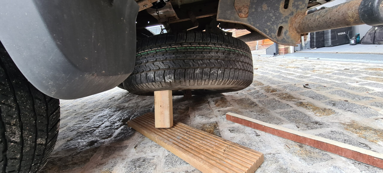 Wheel chocked up to access winch chain securing plate