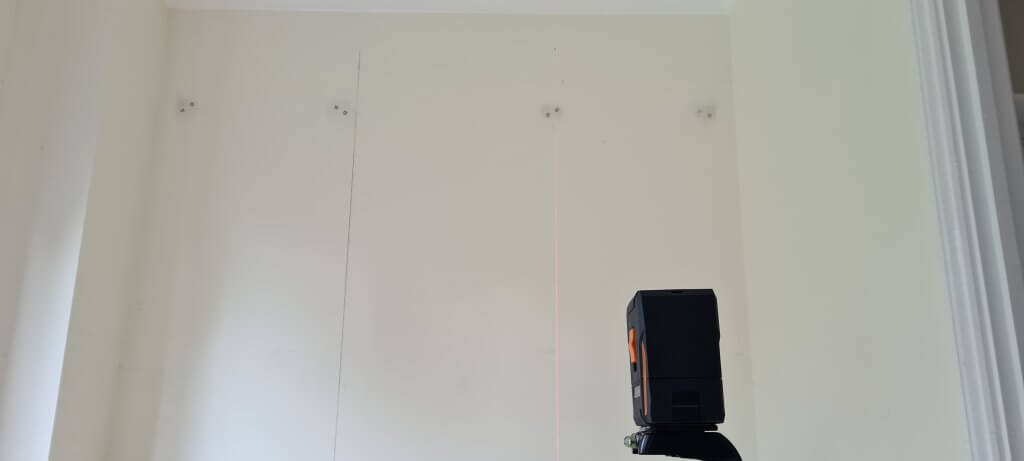 Marking up where the edge of the wallpaper will go with a laser level